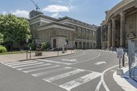 the cross walk in front of a building on a sunny day with clouds in the sky