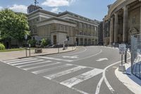 the cross walk in front of a building on a sunny day with clouds in the sky