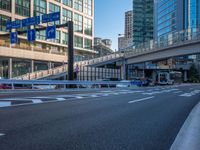 an empty road with a street sign at the curb in front of an office building