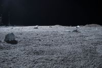 an astronaut walking in the dark on a moon area with rocks and other debris lying around