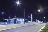 the empty street at night near a city building lit with street lights and a parking lot