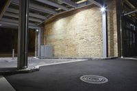 the door to an empty office building illuminated by street lights at night with a manholed sewer on the sidewalk