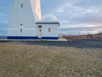 the white lighthouse house with a car parked next to it in front of it at sunset