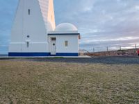 the white lighthouse house with a car parked next to it in front of it at sunset