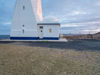 the white lighthouse house with a car parked next to it in front of it at sunset