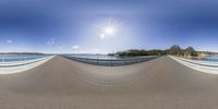 a wide angle view of the road with the sun in the sky on the other side