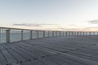 a person sits on a bench next to the ocean in the morning, and looks over the boardwalk