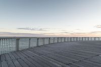 a person sits on a bench next to the ocean in the morning, and looks over the boardwalk