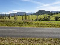 a country road on a mountain pass with fields and hills in the background in a scenic area with trees and grass