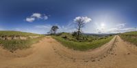 a 360 - view photo of two dirt tracks in a field, with mountains in the distance