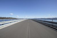 an empty bridge with a long view in the background of water, mountains and a bright sky