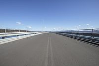 an empty bridge with a long view in the background of water, mountains and a bright sky