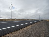 a paved road in front of utility poles on a cloudy day in southern dakotas