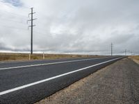 a paved road in front of utility poles on a cloudy day in southern dakotas