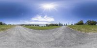 a road on a sunny day with a big sky in the background and many trees around