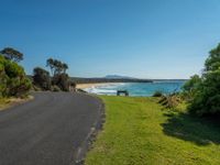 a bench sits on the edge of the empty road by the water's edge