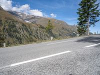 the lone white motorcycle is parked next to the road with mountains in the background and clouds on the sky