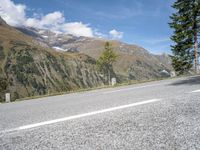 the lone white motorcycle is parked next to the road with mountains in the background and clouds on the sky