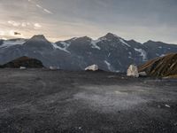 a black and white photo of a camp site and the mountains in the background as the sun sets