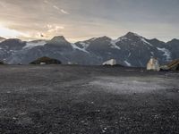 a black and white photo of a camp site and the mountains in the background as the sun sets