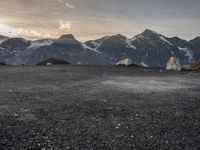 a black and white photo of a camp site and the mountains in the background as the sun sets