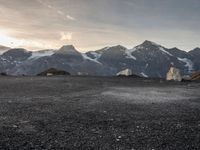 a black and white photo of a camp site and the mountains in the background as the sun sets