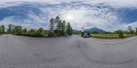 fisheye lens of a street with cars driving on it, and a mountain in the background