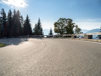 an empty asphalt road near a tree filled area and sky with clouds in the background