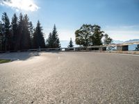 an empty asphalt road near a tree filled area and sky with clouds in the background