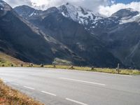 a motorcycle riding down a street with mountain in the background next to a highway and road sign