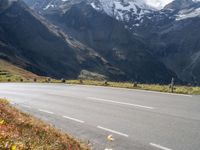 a motorcycle riding down a street with mountain in the background next to a highway and road sign