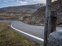 a long country road with two cars stopped on the side of it in front of mountain range