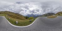 a view from the inside looking up at a curve in the road with a sky full of clouds and mountains