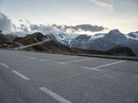 a lone road leads up to a mountain with snow covered mountains in the background and mountains