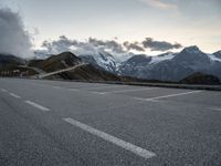 a lone road leads up to a mountain with snow covered mountains in the background and mountains