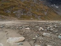 an image of a mountain scene with some rocks in the foreground and snow on top