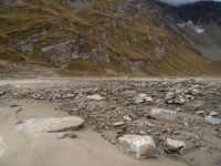 an image of a mountain scene with some rocks in the foreground and snow on top