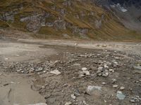 an image of a mountain scene with some rocks in the foreground and snow on top