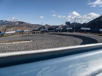 view from inside a vehicle at a stop and mountain top with buildings and road signs