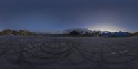 an intersection with snow capped mountains and cloudy sky in the background, on top of a small road