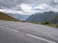 an empty parking lot on the edge of a mountain road on a cloudy day with mountains in the background