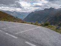 an empty parking lot on the edge of a mountain road on a cloudy day with mountains in the background