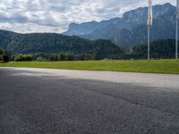 an empty street with flags on either side of the road and mountains in the background