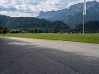 an empty street with flags on either side of the road and mountains in the background