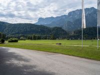 an empty street with flags on either side of the road and mountains in the background