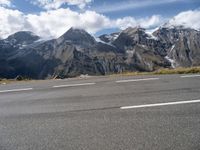 a person riding a skateboard down an empty road with snowy mountains behind him on a cloudy day