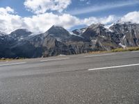 a person riding a skateboard down an empty road with snowy mountains behind him on a cloudy day