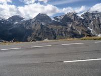 a person riding a skateboard down an empty road with snowy mountains behind him on a cloudy day