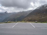 a lone skateboard parked in the middle of a road with mountains and foggy clouds