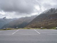 a lone skateboard parked in the middle of a road with mountains and foggy clouds